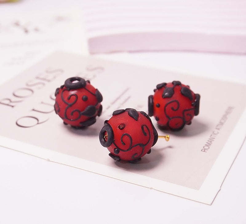 Three red and black patterned glass bead earrings on a white card with decorative text