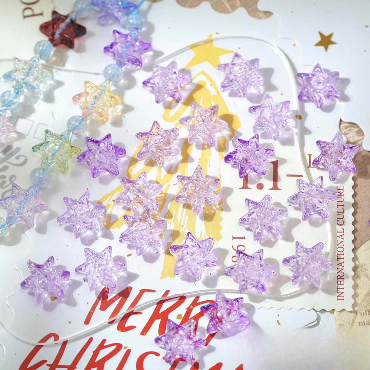 Translucent star-shaped glass beads in pastel and purple shades on a Christmas card