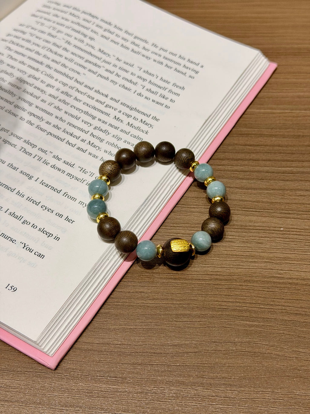 Blue Water Jadeite & Sandalwood Bracelet held over open book