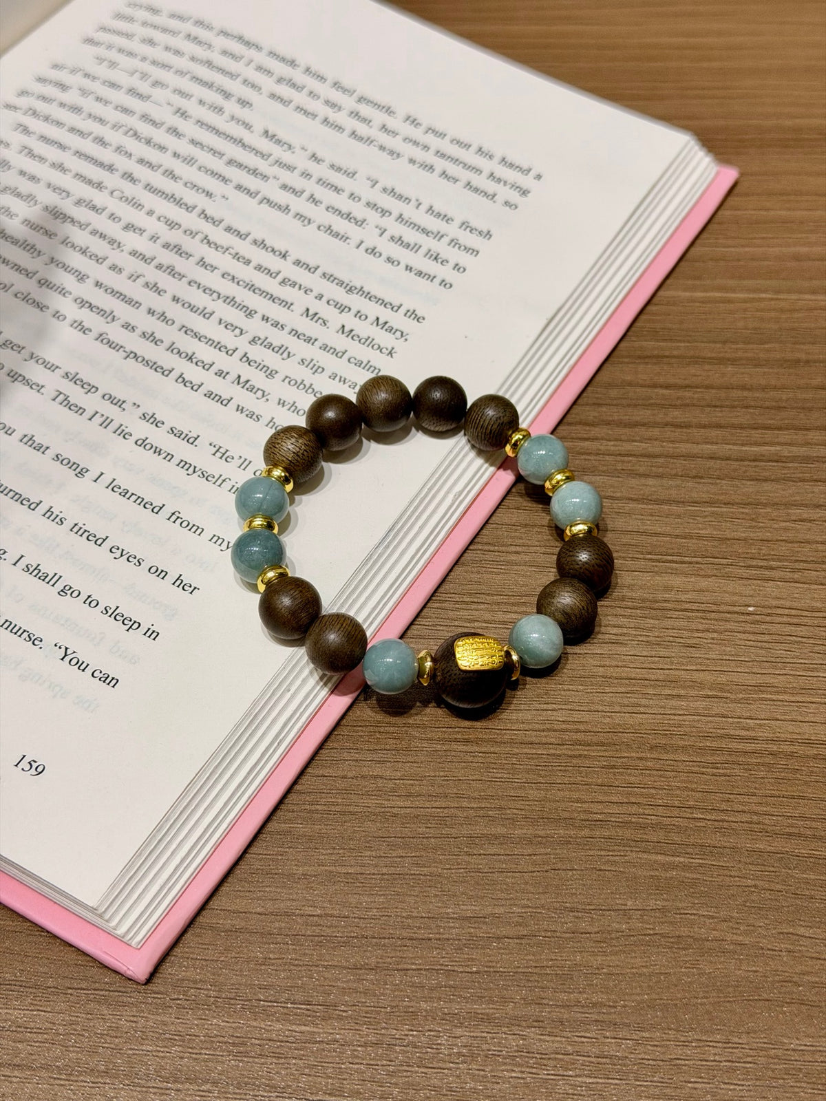 Blue Water Jadeite & Sandalwood Bracelet held over open book