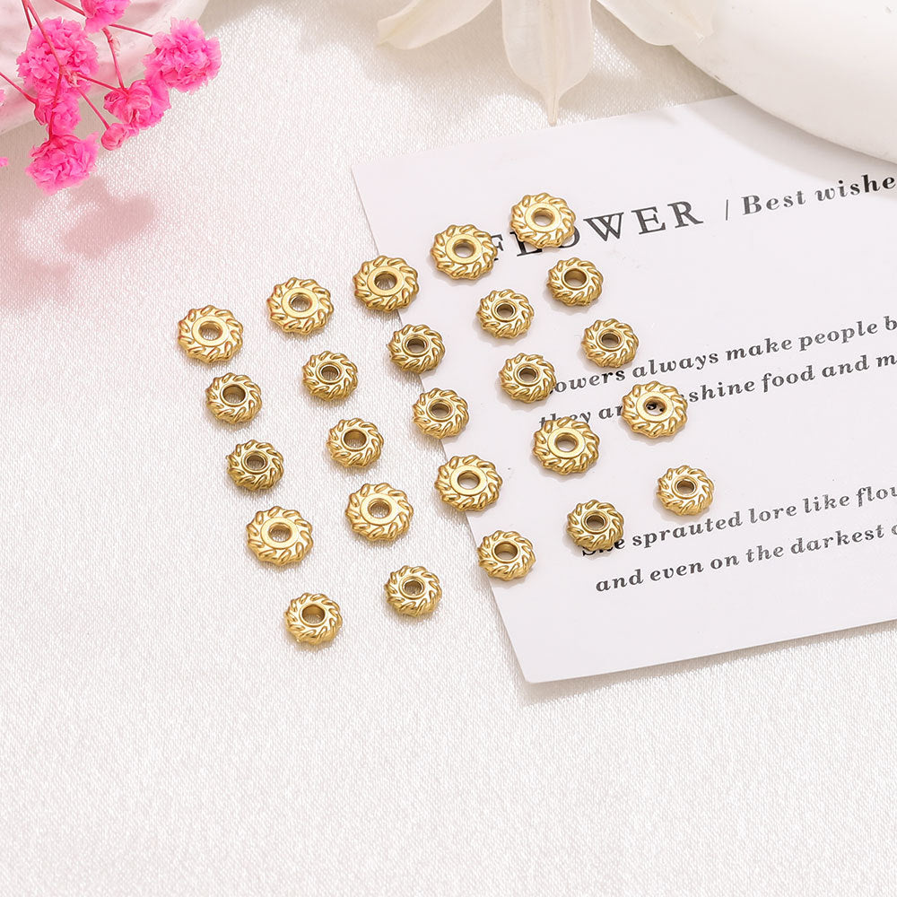 Small gold-toned circular spacer beads with a floral sunburst engraved pattern arranged in a set