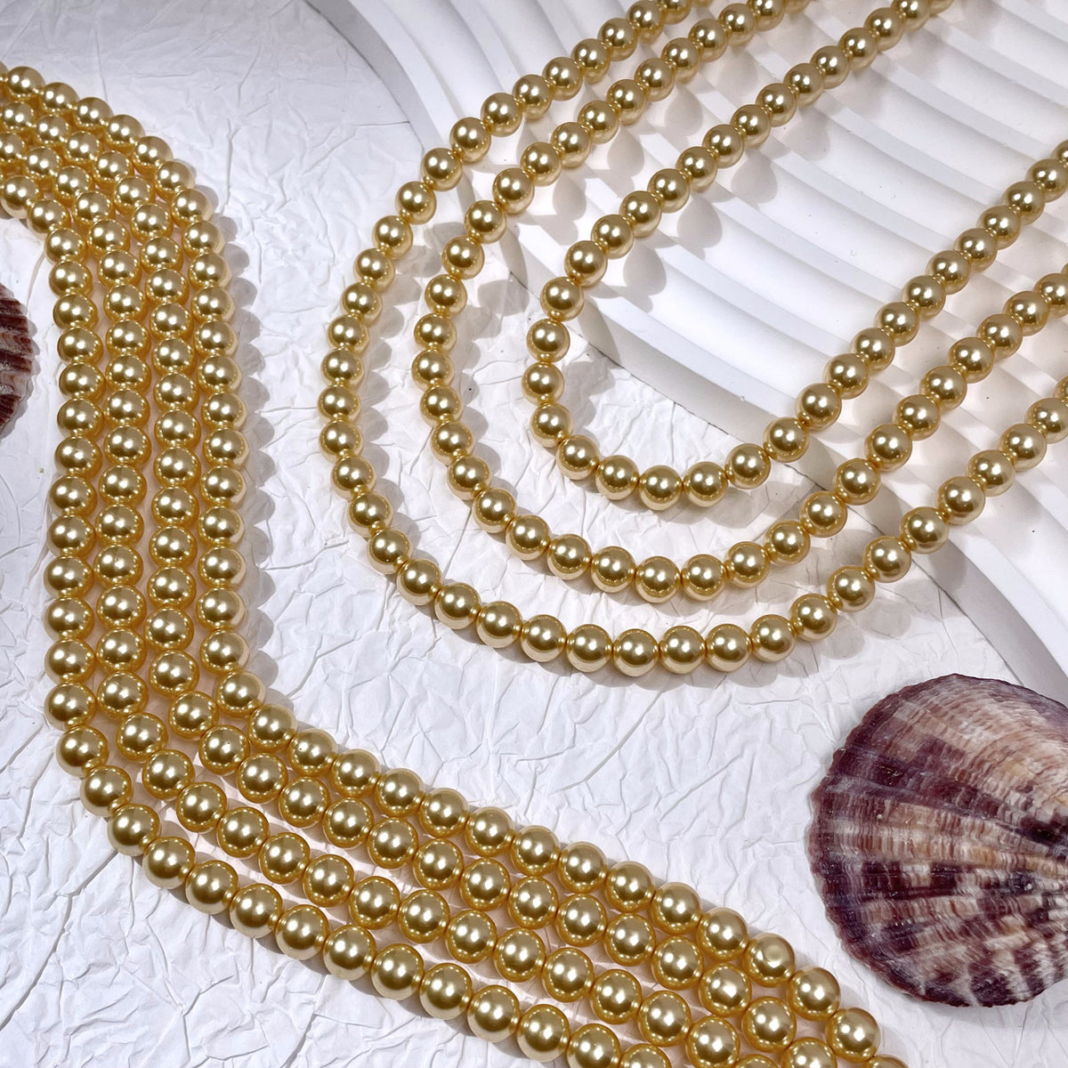 Multiple strands of round gold-toned glass pearl beads with seashell