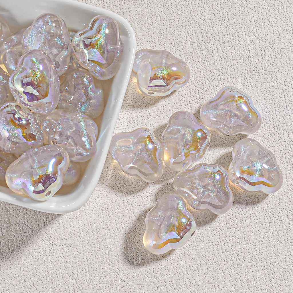 Pearly white cloud-shaped resin beads with gold and purple iridescence in a white dish on beige fabric
