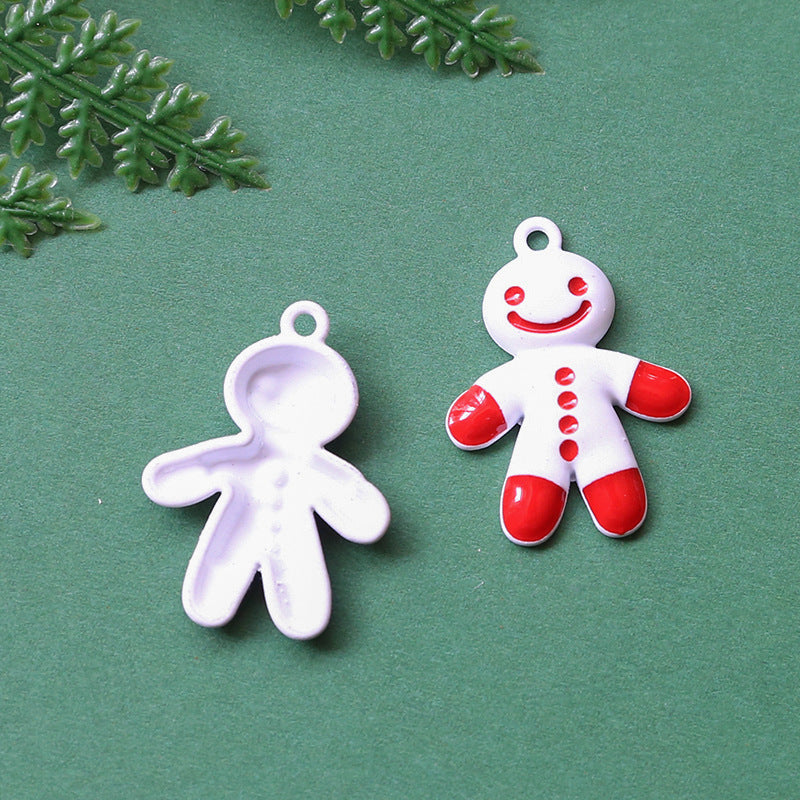 Two small gingerbread person charms on green background, white enamel