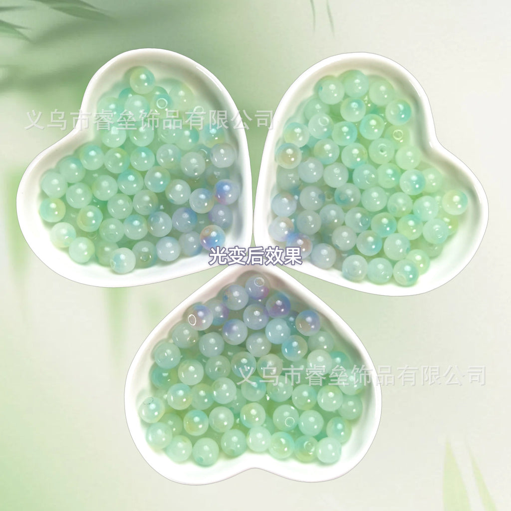 Three heart-shaped dishes of iridescent pale green and mint beads on light green