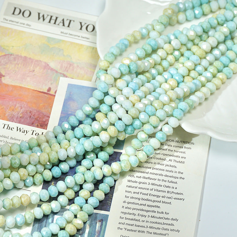 Strands of iridescent light blue-green faceted porcelain beads on printed book pages