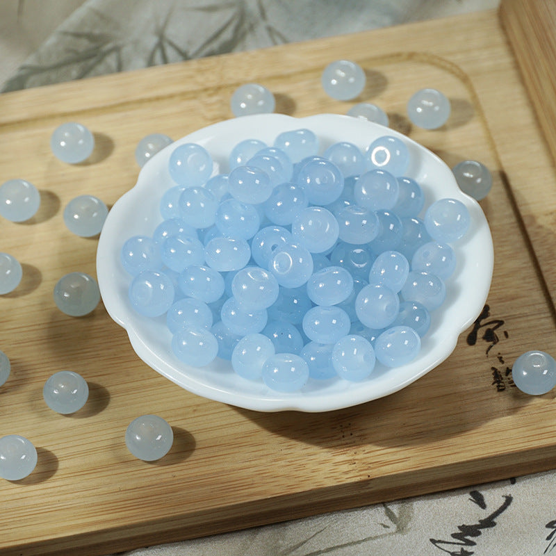 Light blue translucent round beads with white pearls in a small white dish on wood