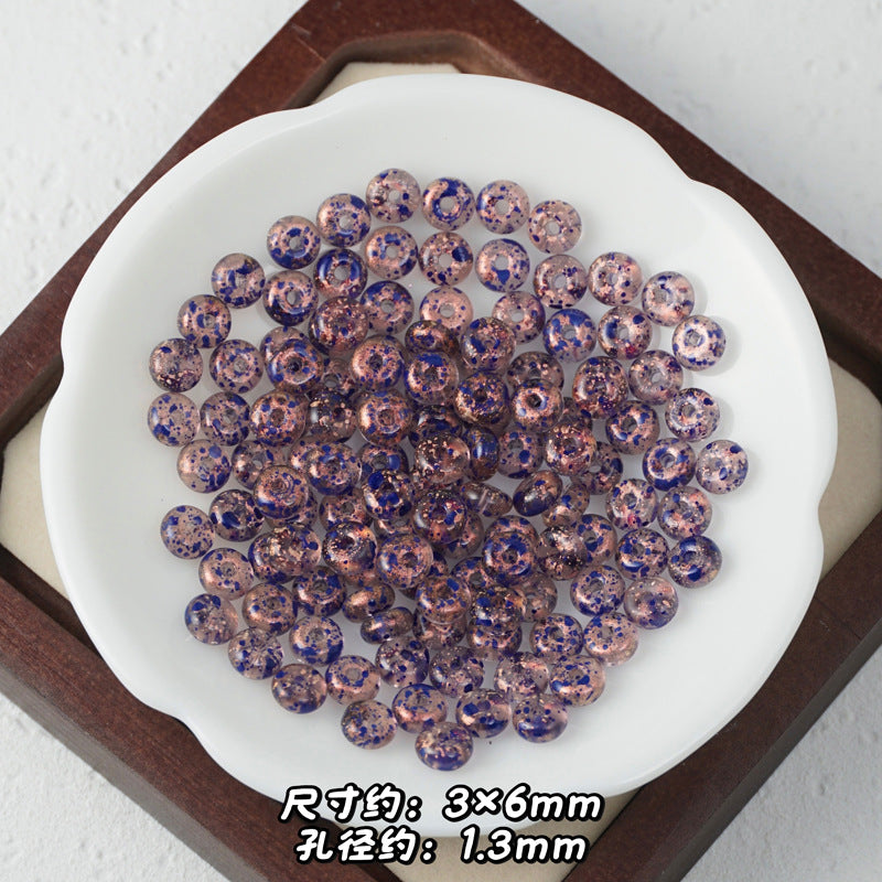 Pinkish-rose Picasso glass abacus beads with dark blue glittery speckles.