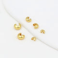 Five small gold C-shaped crimp bead covers scattered on a white background