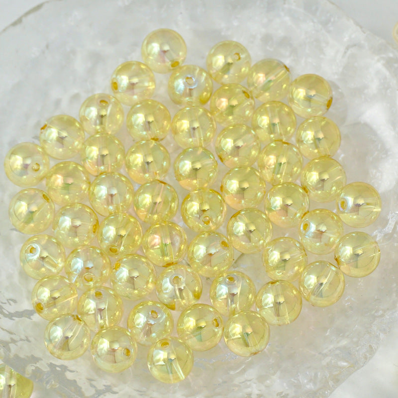 A pile of round, iridescent pale yellow beads resting on a textured white surface.