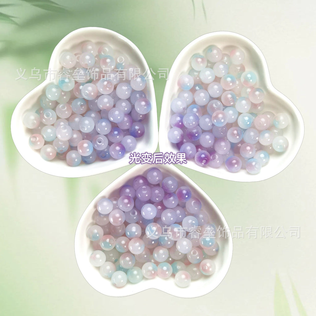 Three heart-shaped bowls of iridescent pastel lavender, pink, blue, and white beads