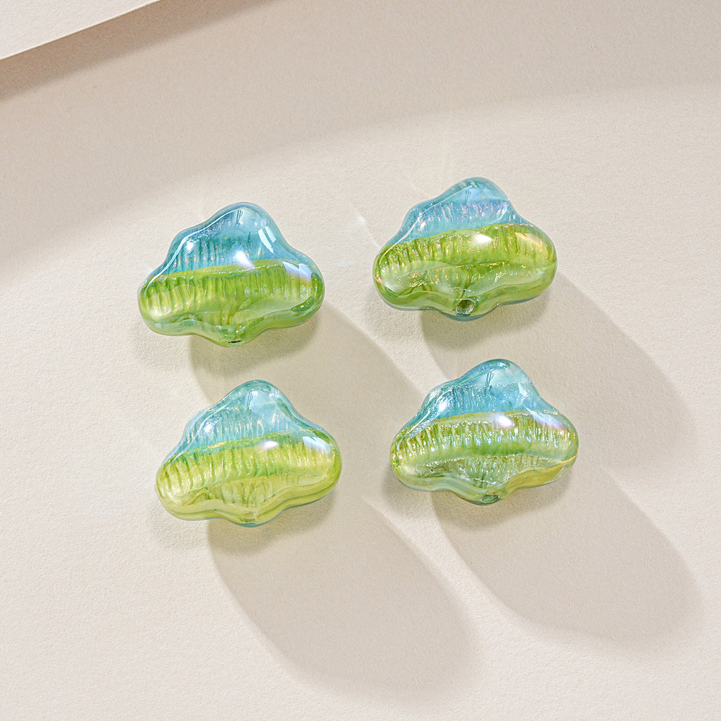 Four cloud-shaped resin focal beads with a light blue to green gradient on a light beige surface.