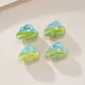Four cloud-shaped resin focal beads with a light blue to green gradient on a light beige surface.