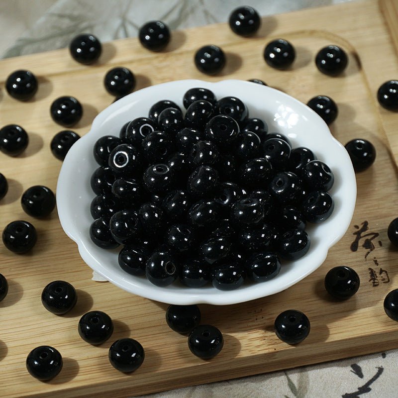 Glossy black round beads in a white ceramic bowl on a wooden board