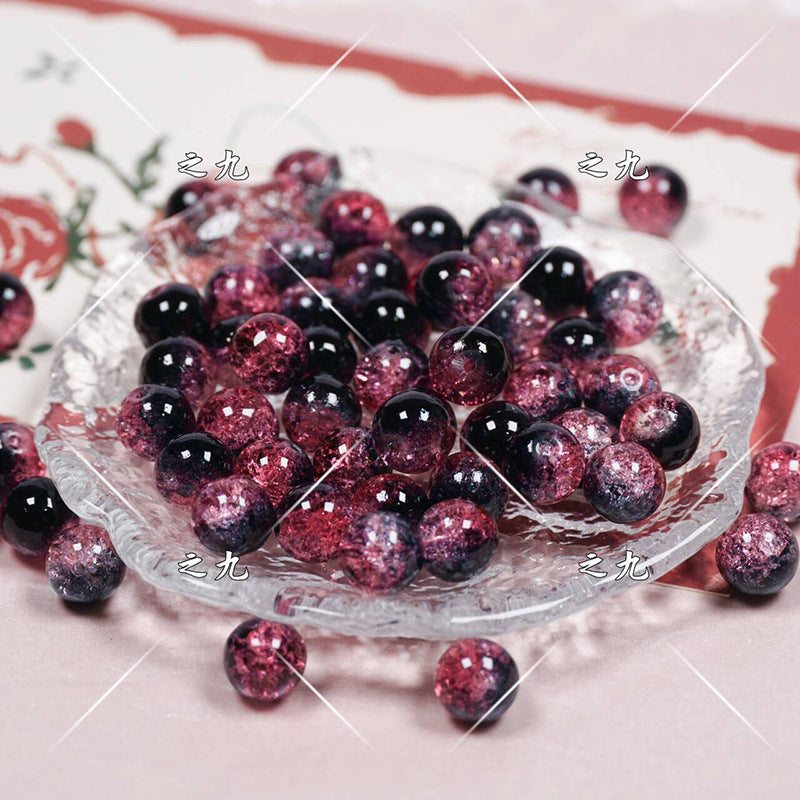 Round glass beads with dark purple to pink gradient and glittery texture on a glass plate