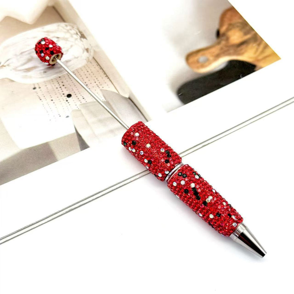 Decorative ballpoint pen with a red rhinestone-covered barrel and silver metal tip on white