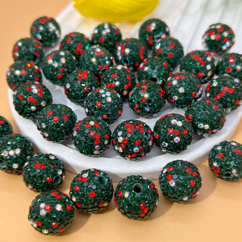 Green glittery Christmas beads with red and silver sparkles on a white plate.