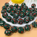 Green glittery Christmas beads with red and silver sparkles on a white plate.