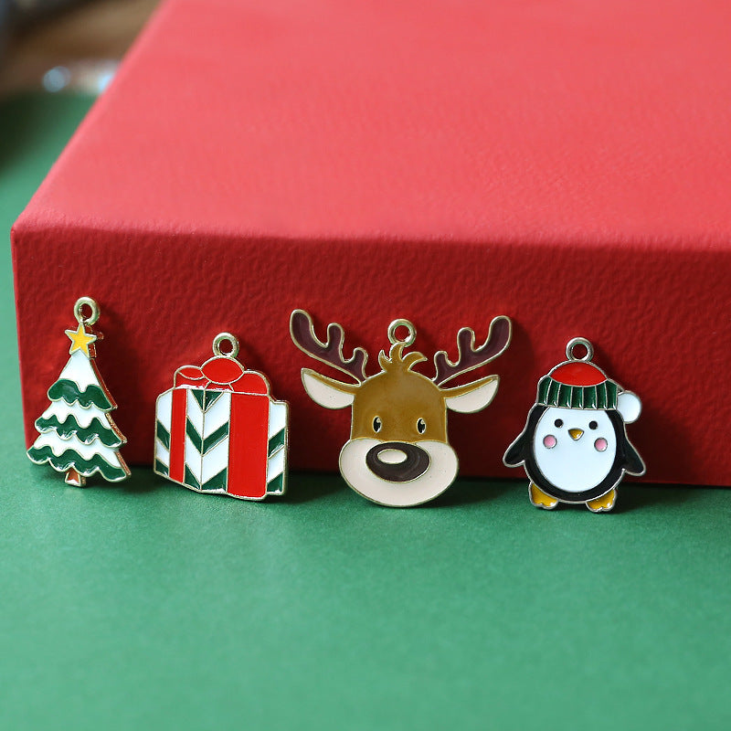 Four Christmas enamel alloy charms on a green surface in front of a red box