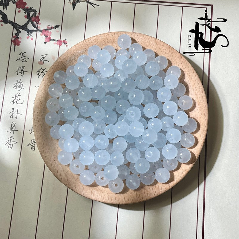 Pale blue translucent round beads in a wooden bowl on textured surface