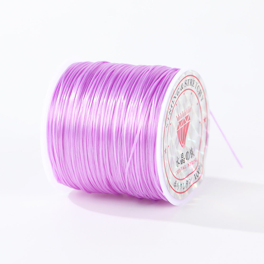 Spool of light purple 0.8mm flat elastic beading cord lying on its side, brand label on the end, white background