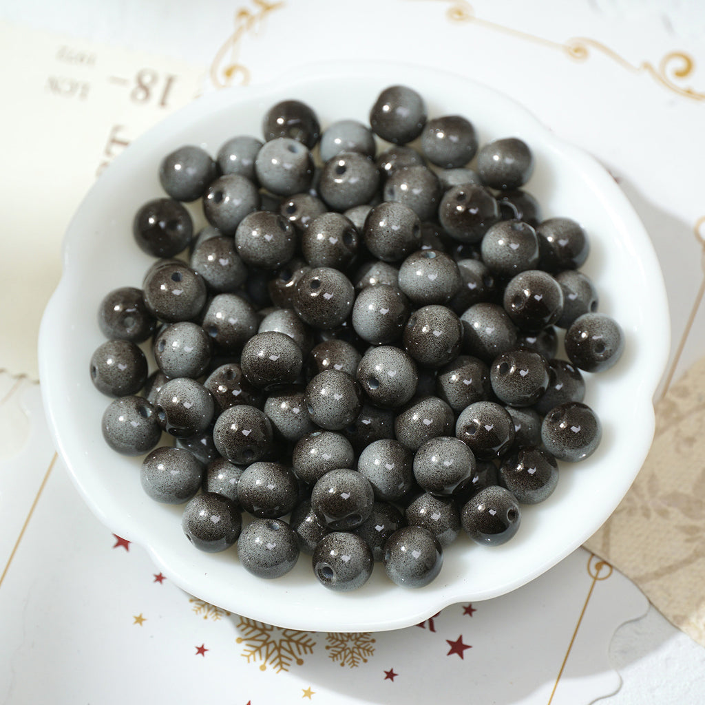 Small round dark gray to black glittery glass beads in a white bowl