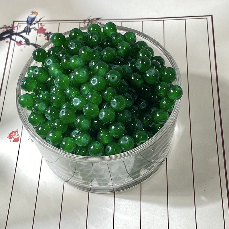 Dark green round beads in a clear container on white surface with black lines