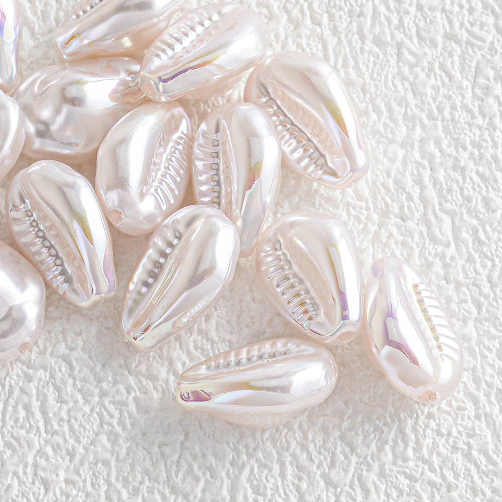 Pile of iridescent cowrie shell beads with a pearlescent finish on a textured white surface