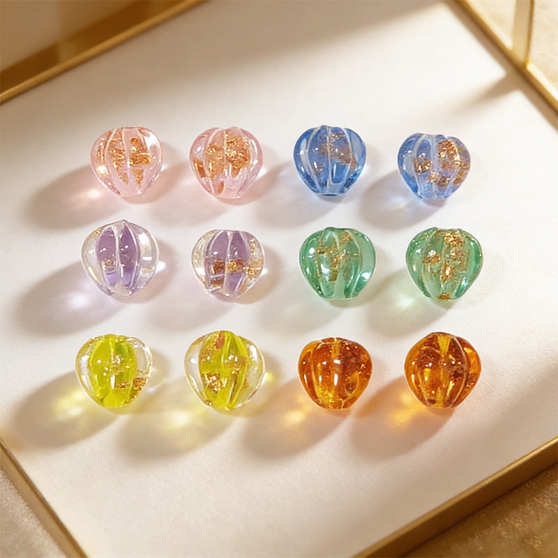 Twelve gold-sand lantern glass beads in assorted colors on a white tray