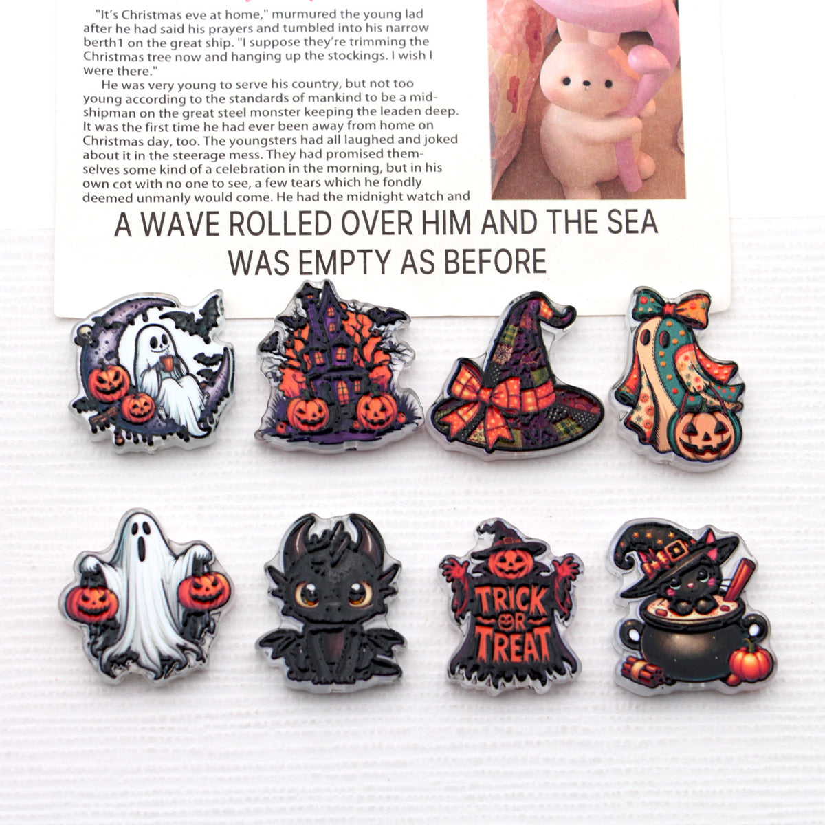 Eight Halloween acrylic beads with ghost, pumpkin, witch hat, and haunted house designs on white