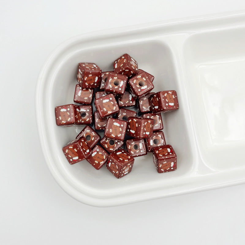 Brown square acrylic beads with gingerbread man prints in a white divided tray