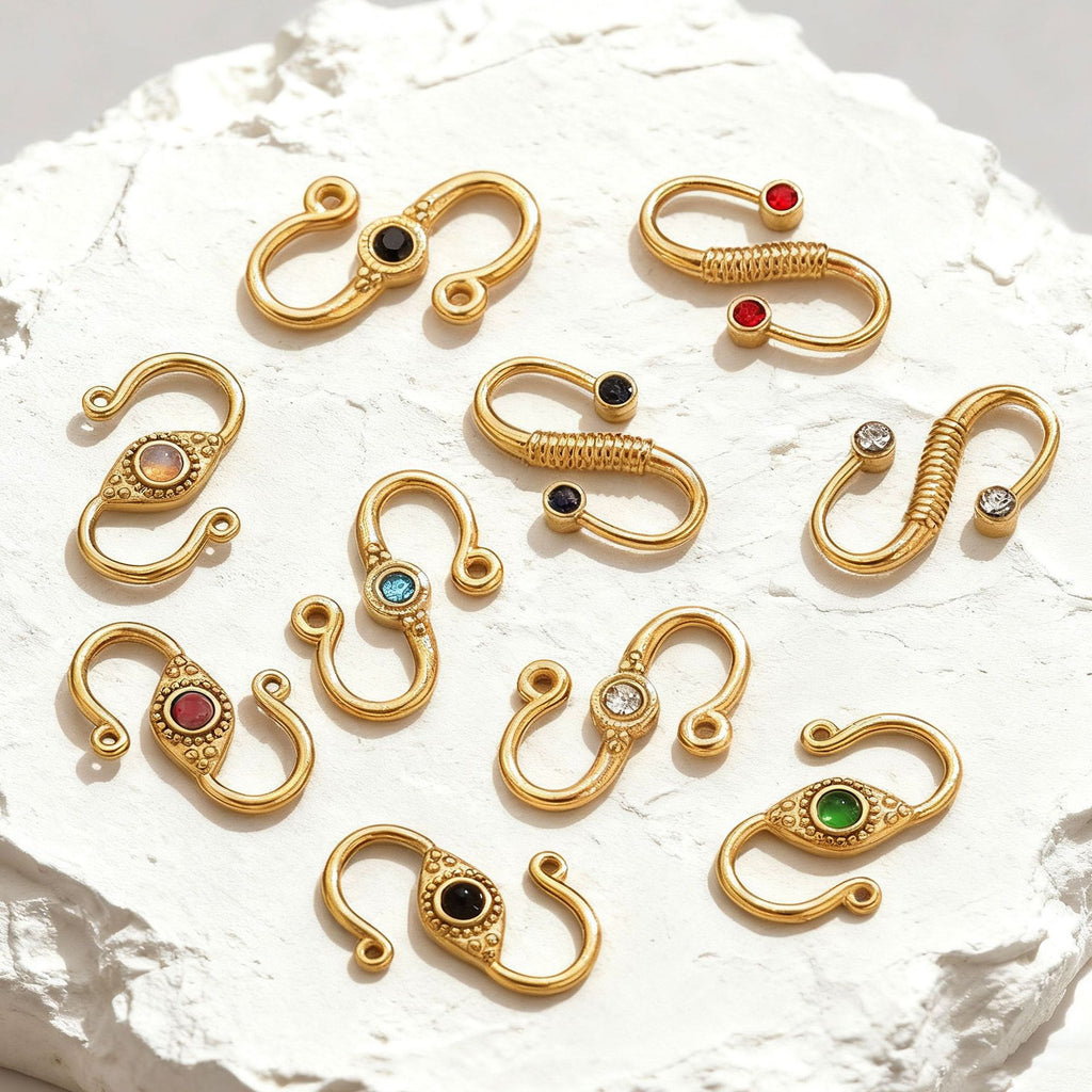 Nine gold stainless steel S-hook jewelry clasps with colorful gemstone inlays on white stone