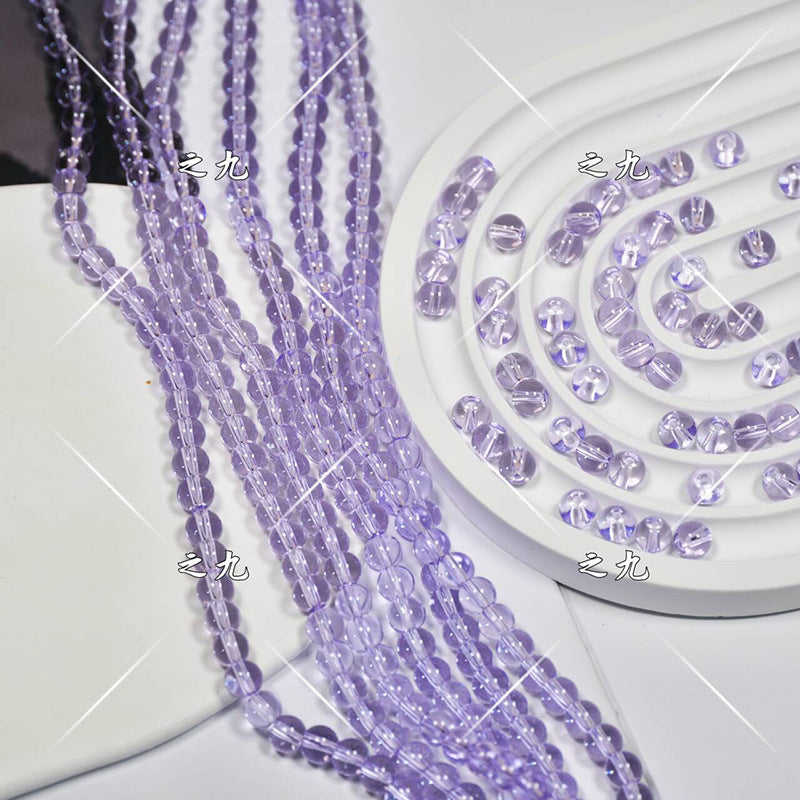 Purple faceted glass beads strung on cords on white spiral tray