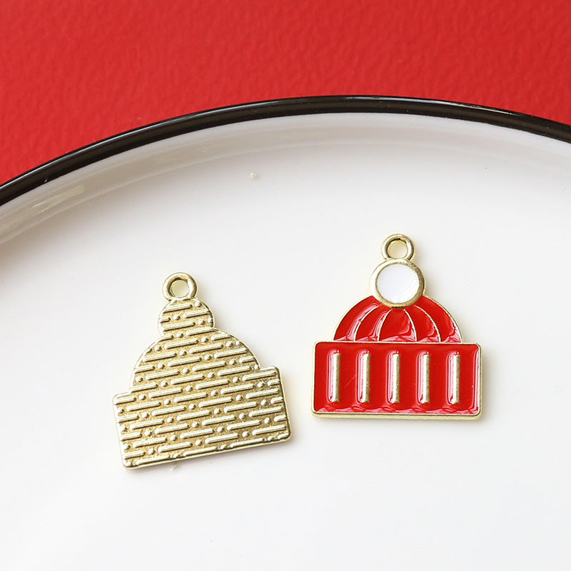 Two small gold-tone architectural charm pendants on white plate with red background