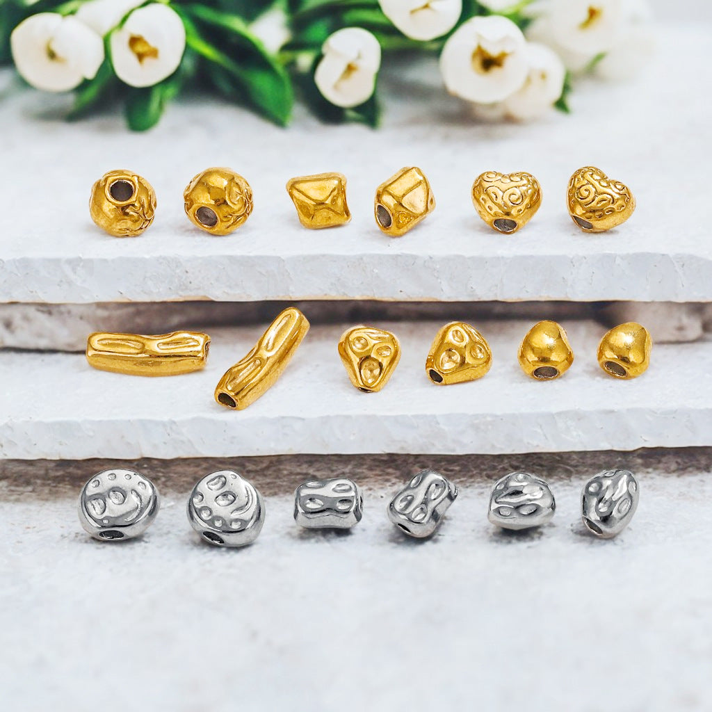 Gold-plated and steel-color baroque irregular spacer beads on a marble surface with white flowers