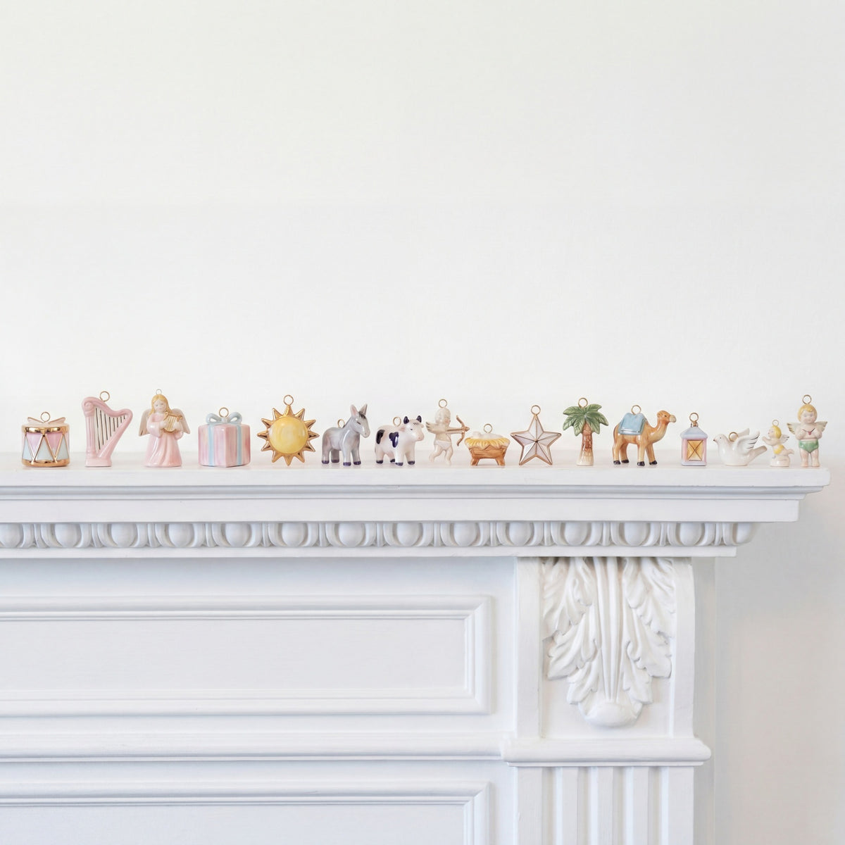 Decorative figurines on a white mantelpiece against a white wall