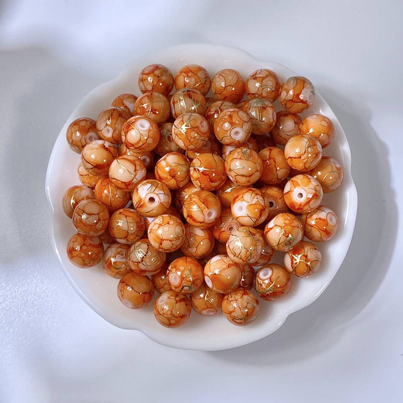 White bowl of marbled amber-orange glass beads with gold-silk veining