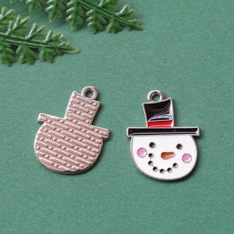 Two silver-toned metal charms on textured green background, mitten shaped