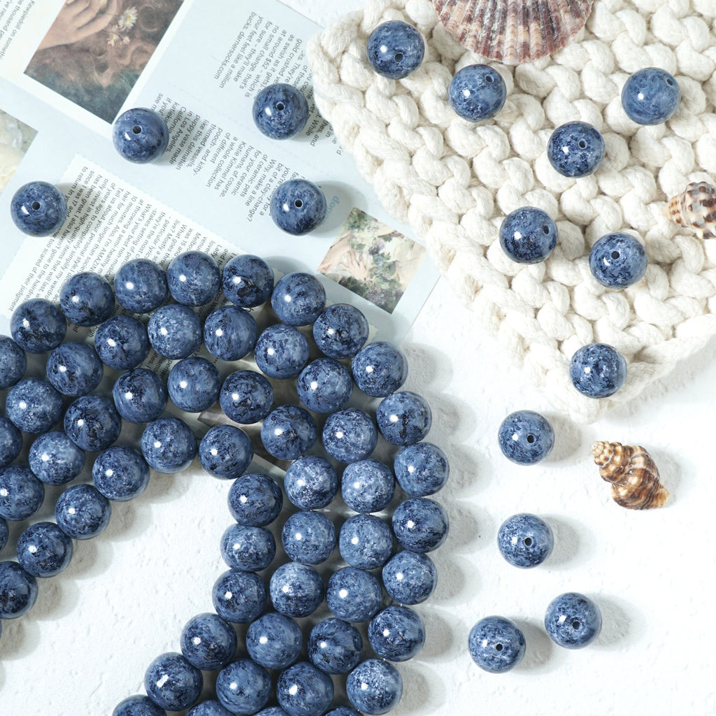 Blue speckled round glass beads with drilled holes on a white surface