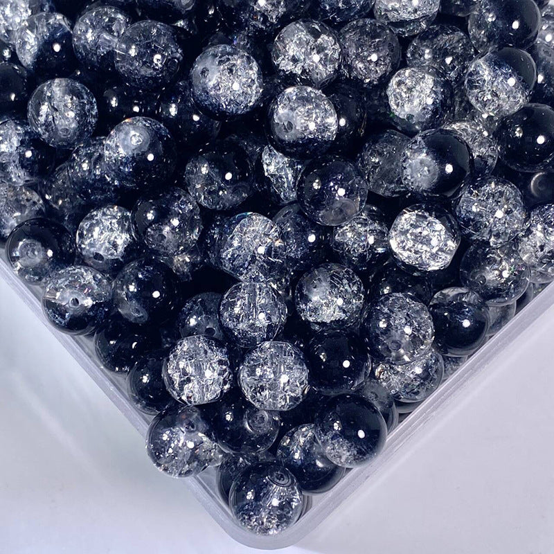 Close-up of mixed round glass beads in a plastic container, navy blue and transparent crackle
