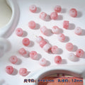 Pink and white marbled round porcelain beads on white ceramic tray, one threaded