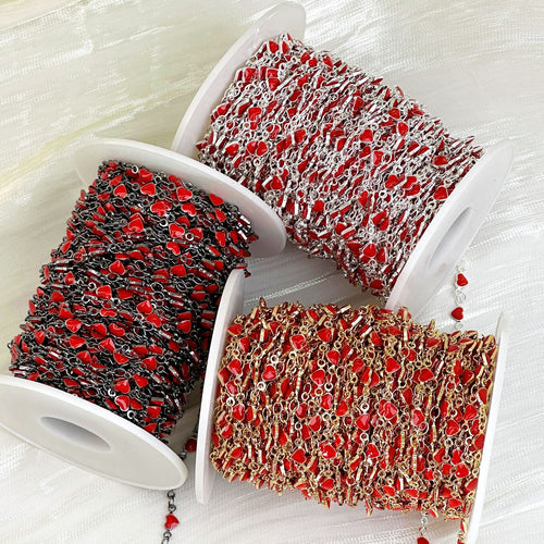 Three spools of red enamel heart station chain in black, silver, and gold metallic tones on white fabric