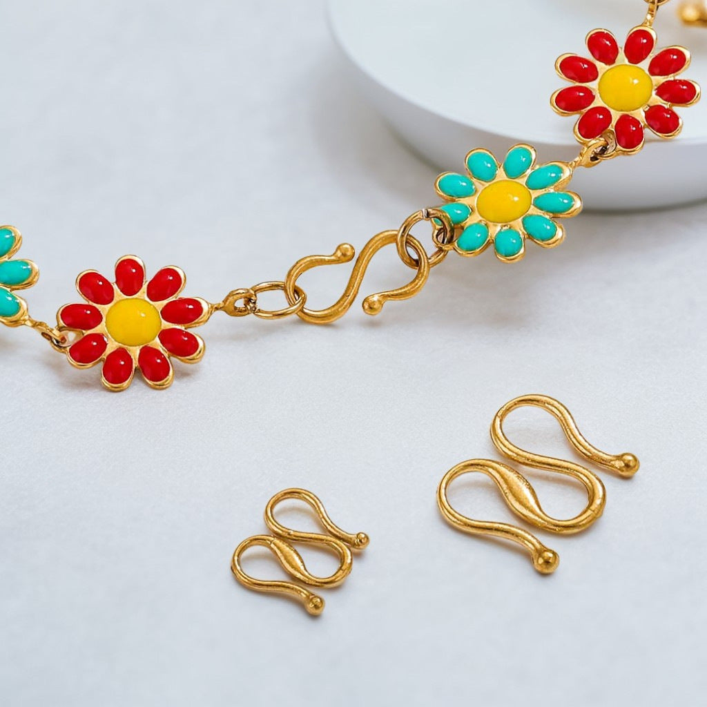 Gold necklace with red and turquoise flower charms and two gold S-hook clasps below, white background.