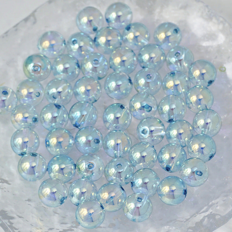 A pile of round, iridescent light blue beads with a pearlescent finish, arranged on a textured white surface.