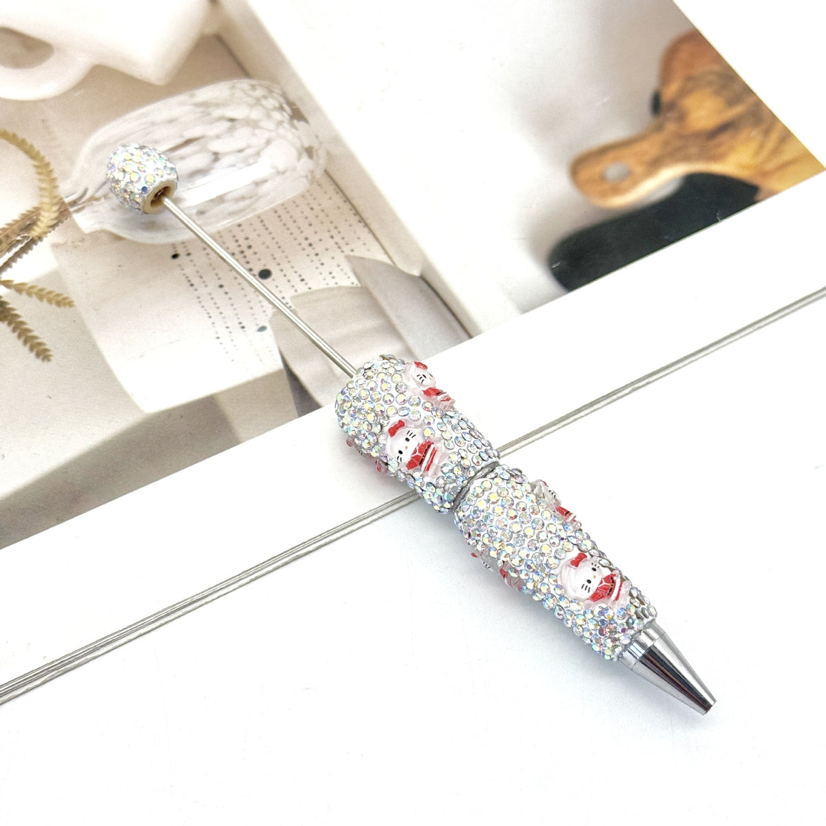 Silver ballpoint pen with clear rhinestones and red-and-white cartoon design.