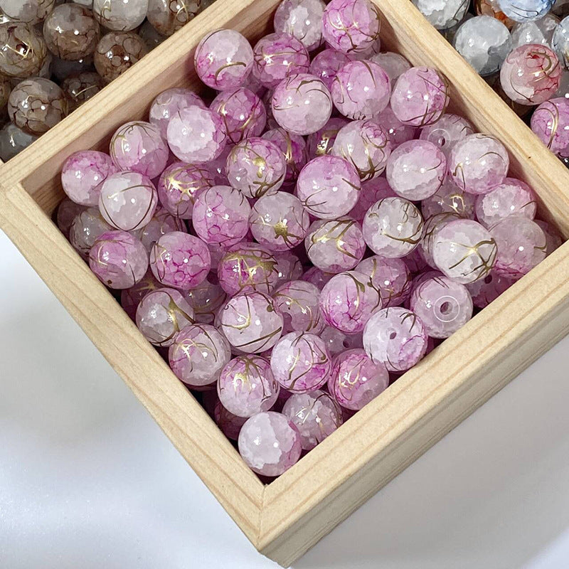 Pink crackle glass beads with gold-silk veins in a wooden tray