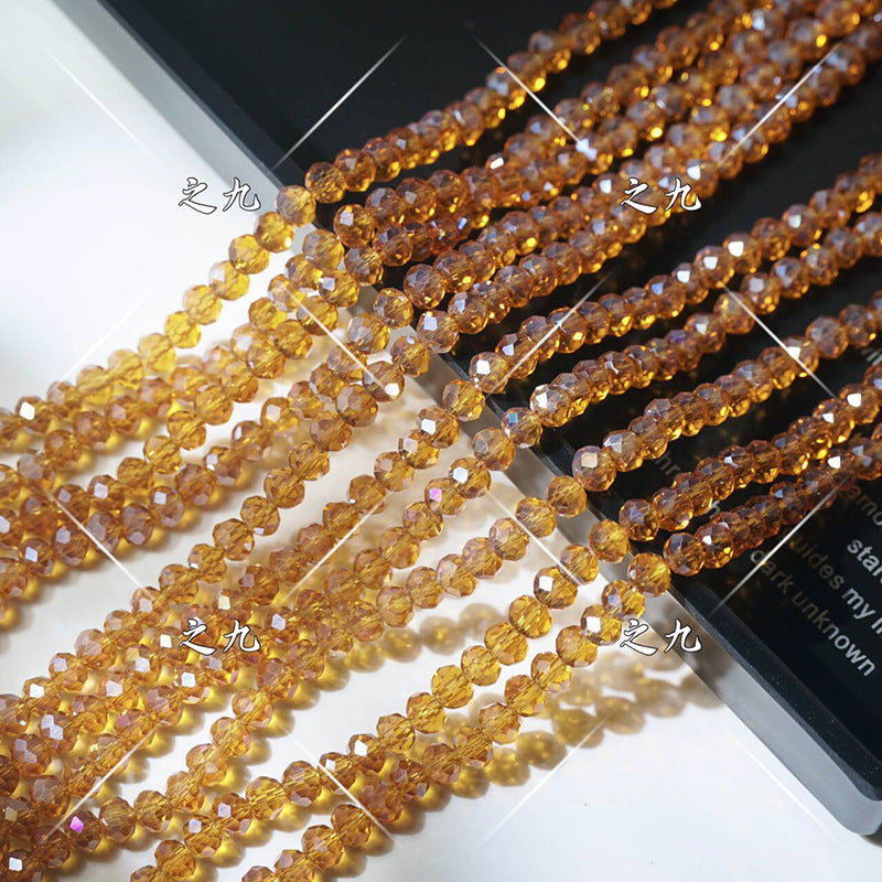 Multiple strands of faceted champagne crystal glass wheel beads arranged diagonally on white surface