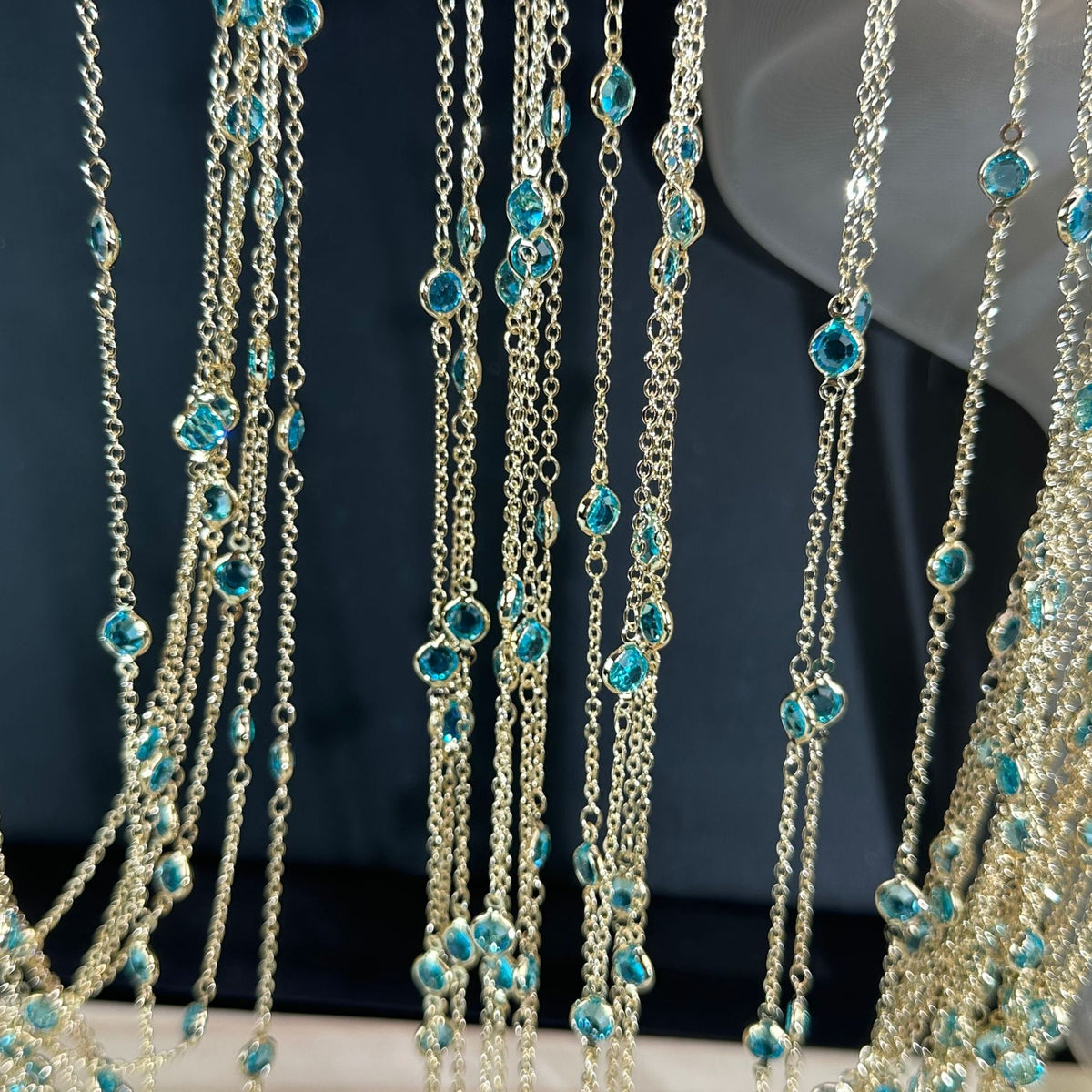 Gold-toned double-strand chain with small turquoise-blue glass beads on dark background