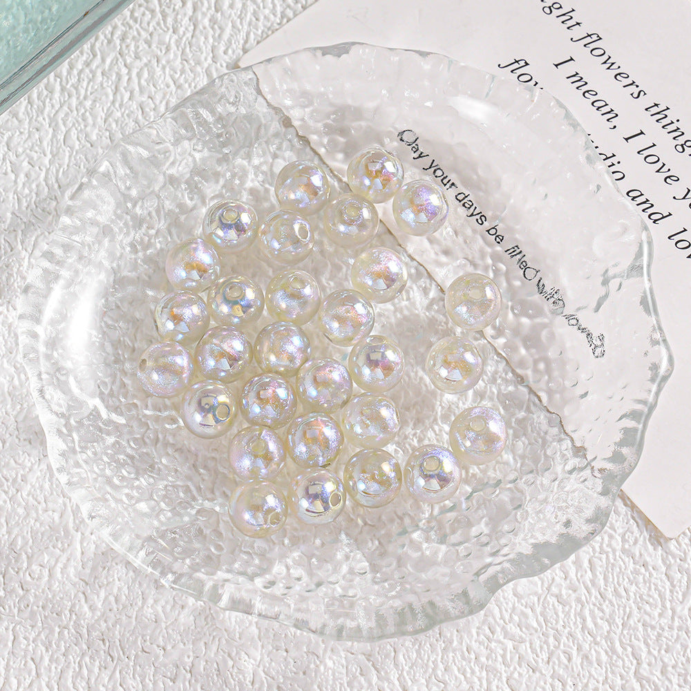 Pile of round iridescent pearl-like beads on textured clear glass plate