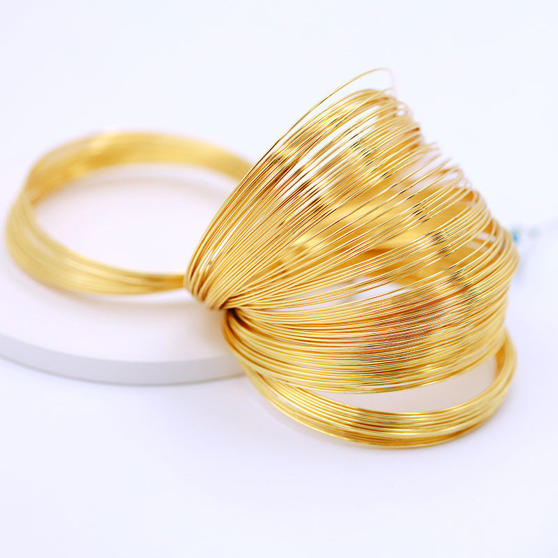 Coiled gold-plated memory wire bracelet ring, 0.6mm thick, 60mm diameter, on white background